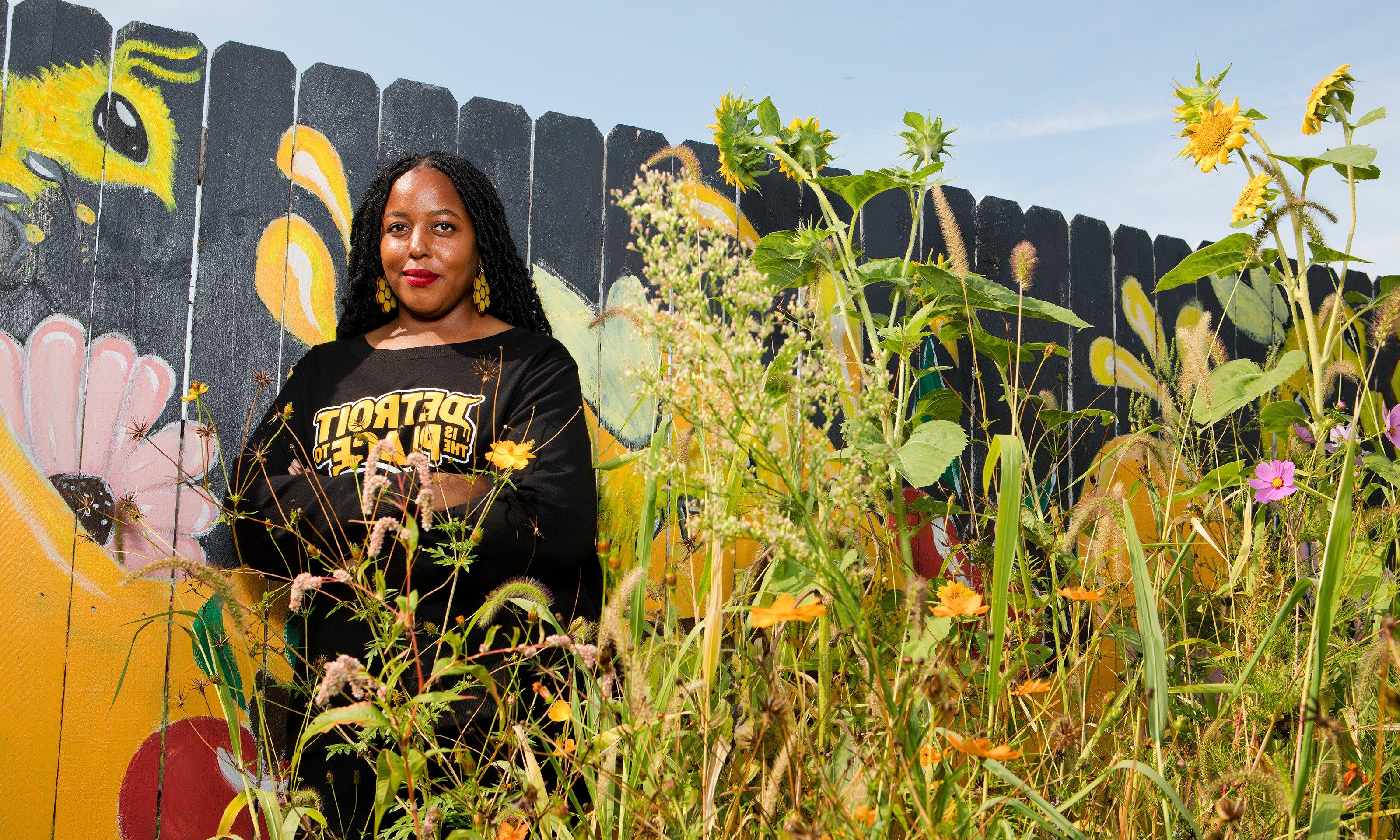 A woman posing alongside wild flowers.