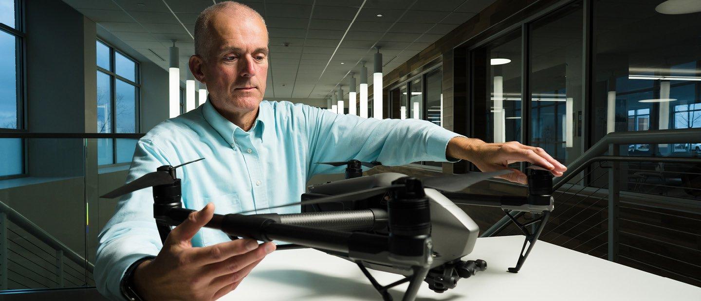 A man seated at a table, holding a drone.