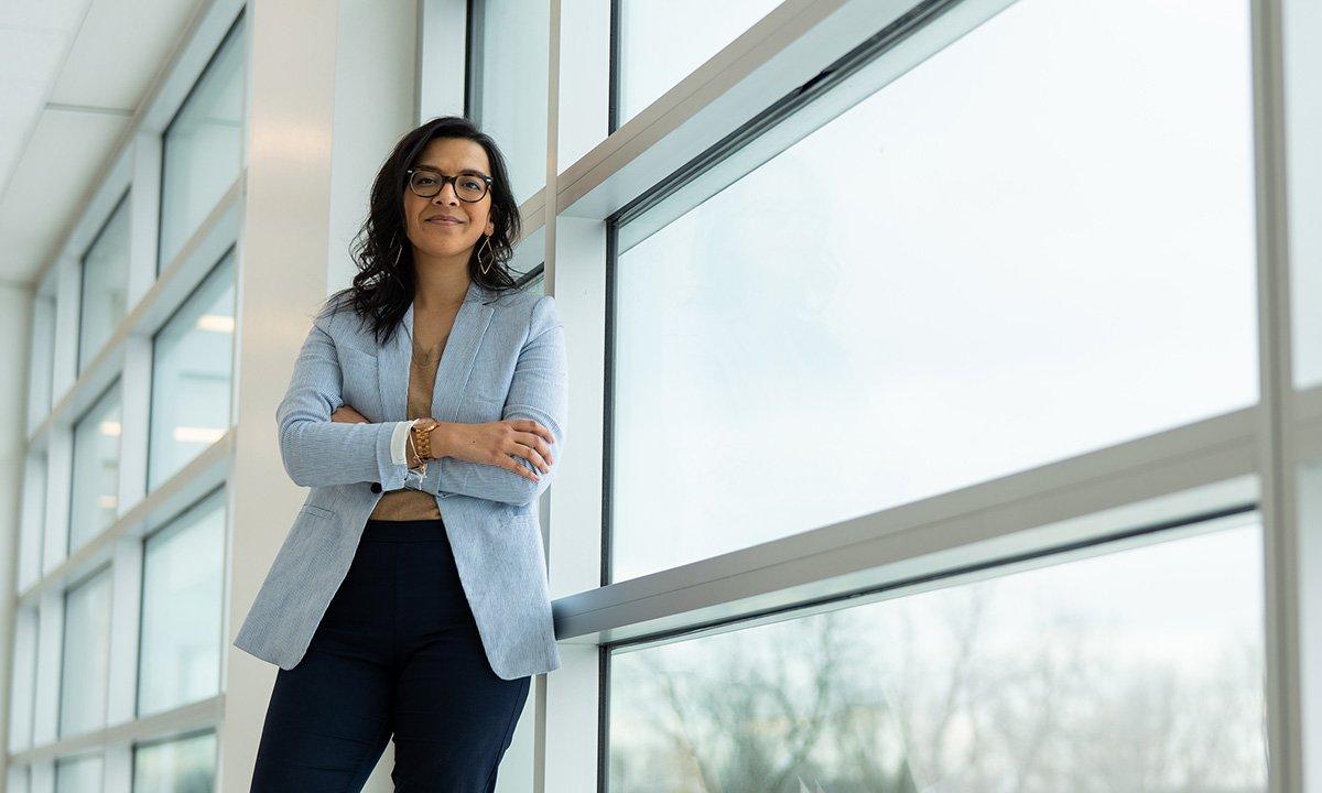 Woman standing and leaning against window smiling at camera